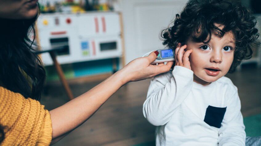 Mother with ear thermometer checking temperature.