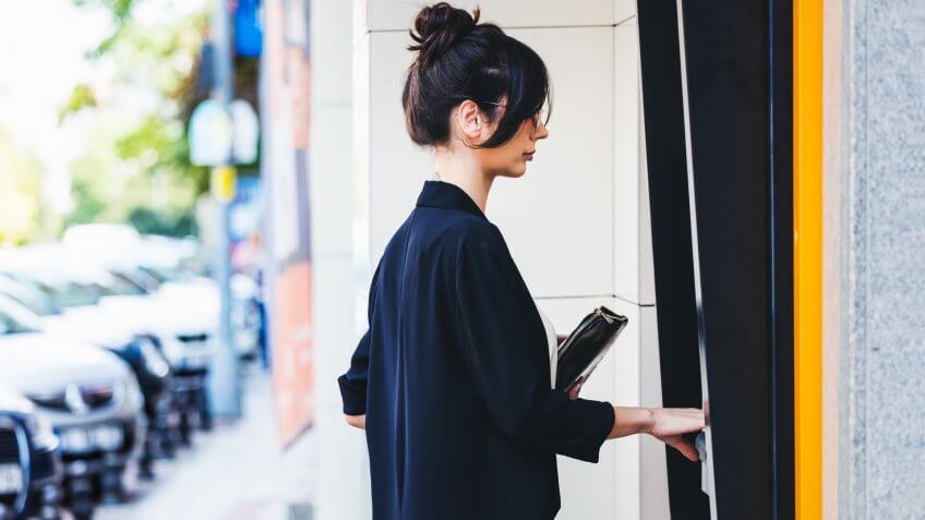 Businesswoman using ATM in city.