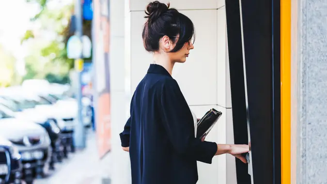 Businesswoman using ATM in city.
