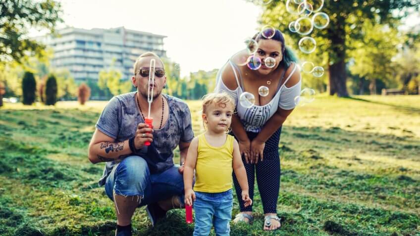 Modern real parents with body positive attitude, tattoos, piercings and positive lifestyle, spending afternoon with their kids in the park.