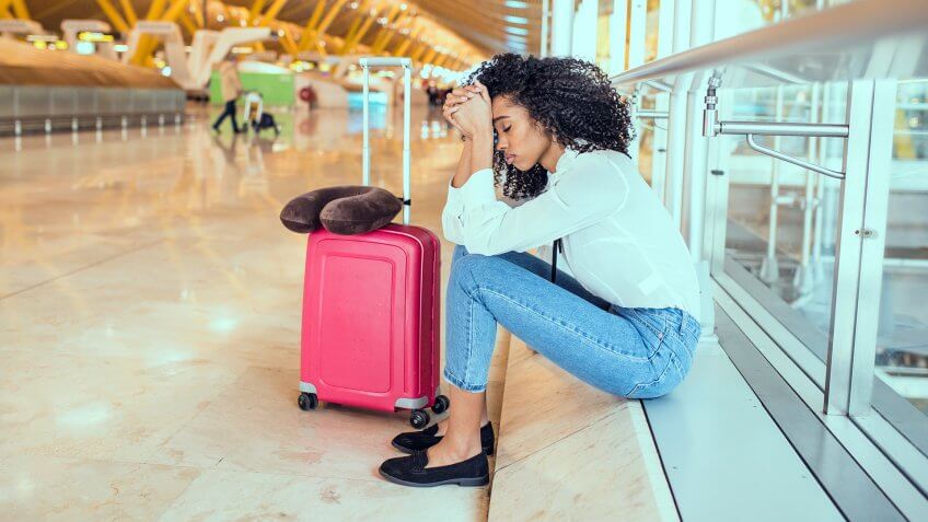 Woman sad and unhappy at the airport with flight canceled.