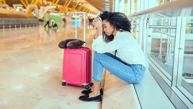 Woman sad and unhappy at the airport with flight canceled.