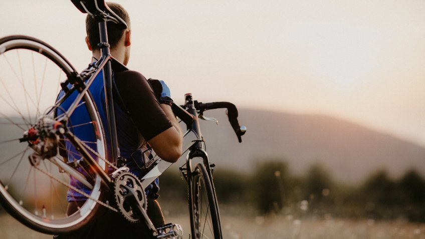 Well built man carrying his bike.