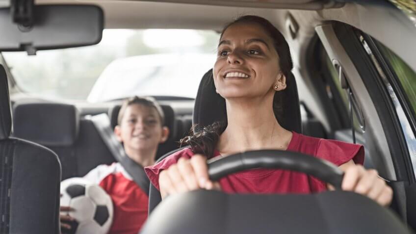 Happy soccer mom transporting kid to football practice in her car â?? lifestyle concepts.