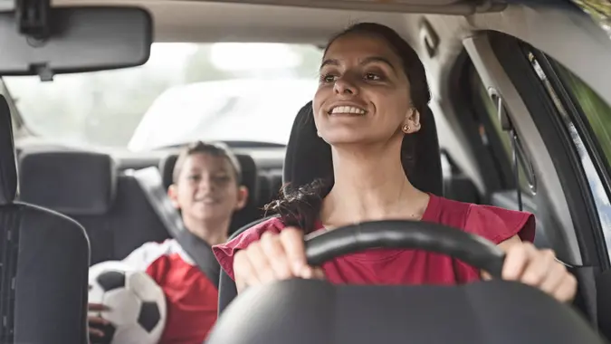 Happy soccer mom transporting kid to football practice in her car â?? lifestyle concepts.