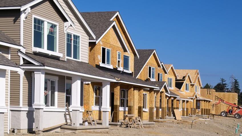 Perspective photo of a row of similar style houses during various phases of construction.