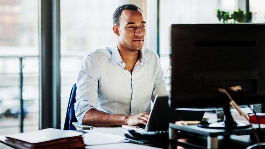 An office worker using working at his desk using a computer to review data.