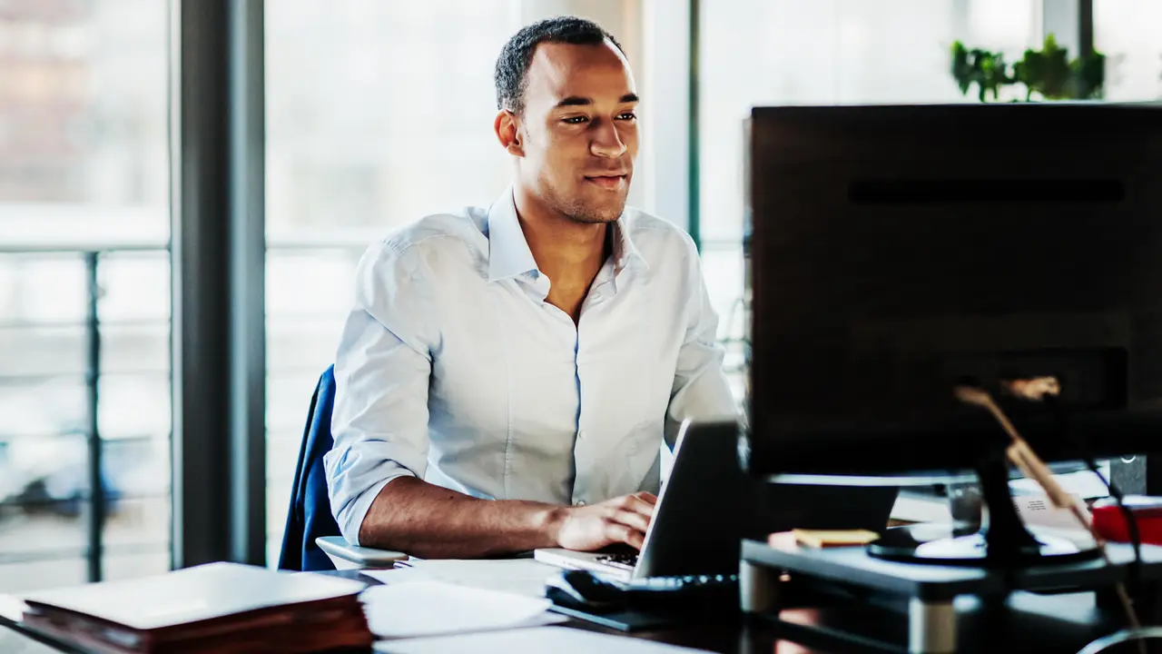 An office worker using working at his desk using a computer to review data.
