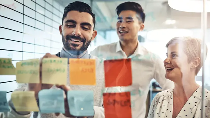Shot of businesspeople brainstorming with sticky notes on a glass wall in the office.
