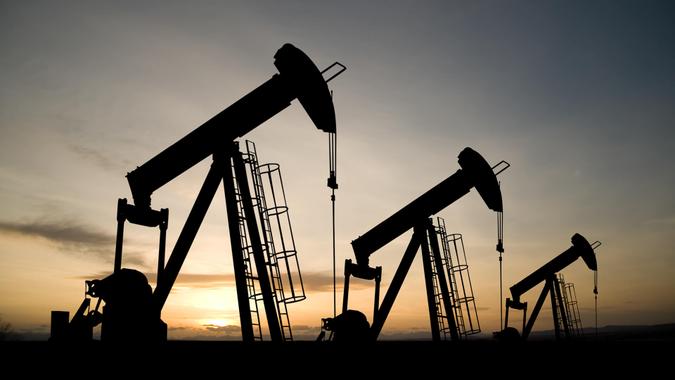 oil industry of three pumpjacks on a prairie at sunrise.