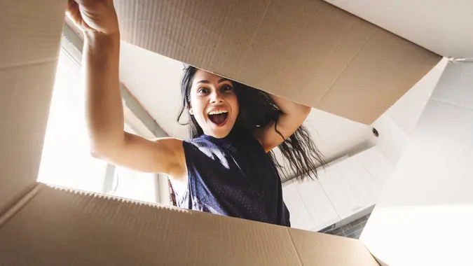 Pretty young happy woman opening a carton box.