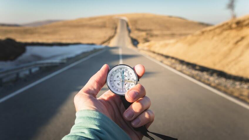 Compass in Hand mountain road background .