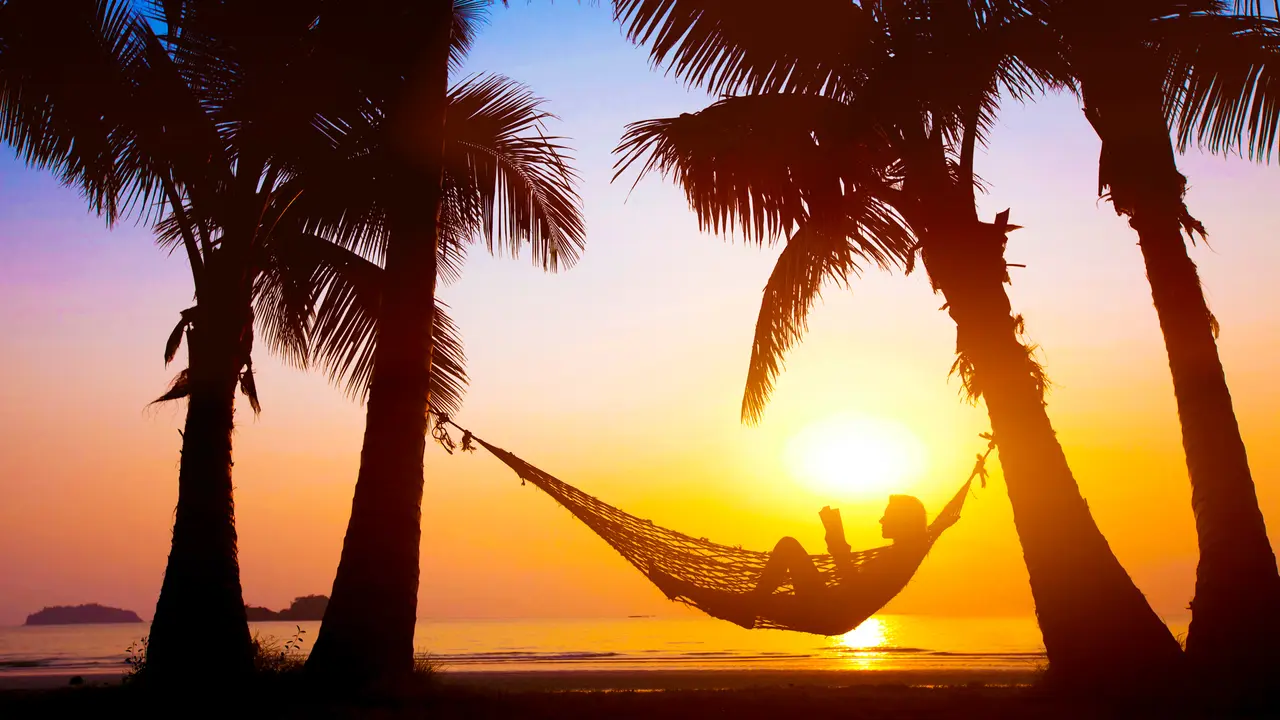 woman relaxing in hammock on beautiful sunset beach, holiday concept.
