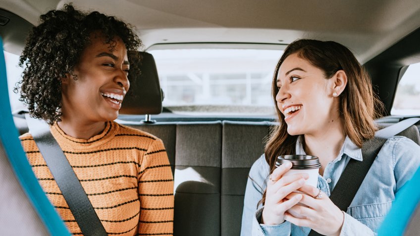 Two friends ride in a crowdsourced taxi, having requested a pick up and drop off on a smartphone.