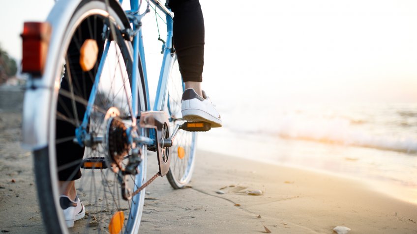 Youn man with classic bike at beach.