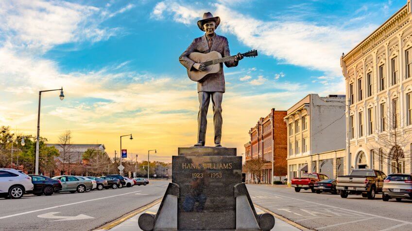 Statue of Hank Williams, the famous country singer, on Commerce Street in Montgomery, Alabama with historic buildings on the right.