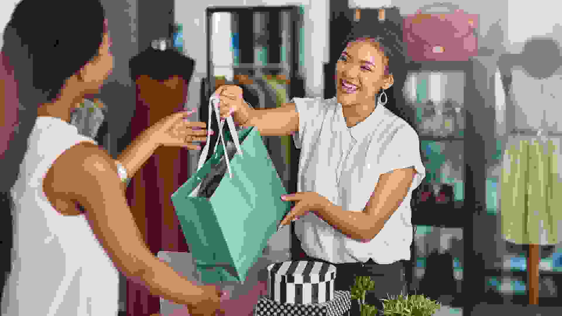 Cropped shot of a young store owner handing a parcel to a customer over the counter.