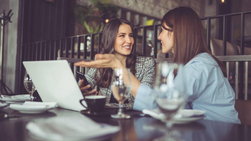 Businesswomen in cafe, using laptop.