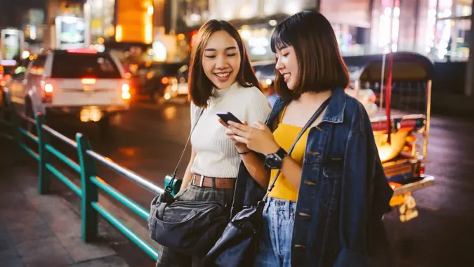 Vintage toned image of two young, Asian women, walking together, chatting, near Siam station on Bangkok Sukhumvit line.