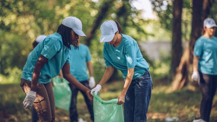 Group of multi-ethnic people, people with differing abilities , volunteers with garbage bags cleaning park area.