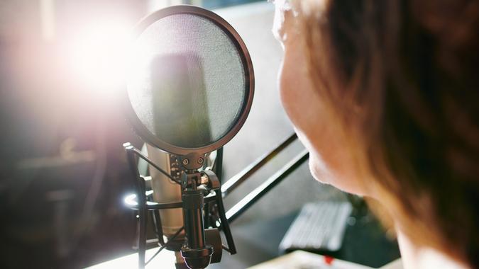 Shot of a woman speaking into a microphone in a recording studio.
