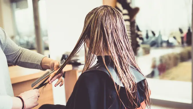Close-up of a woman in hair salon getting her hair cut by the hairdresser.