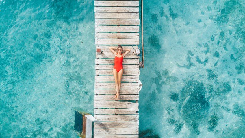 Aerial shot of womann relaxing in a water bungalow.