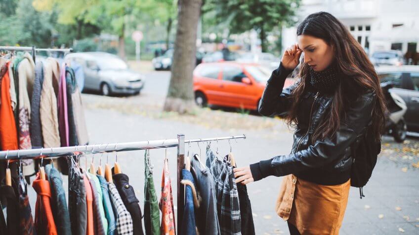 Vintage toned portrait of a young woman in Berlin, wearing a black leather jacket and a beige skirt, walking down the street in Berlin Kreuzberg district in the late Autumn day, shopping on the street market.