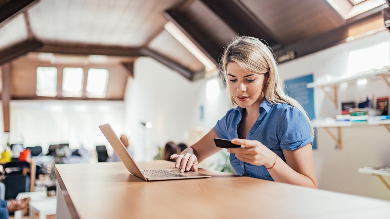 Lovely blonde woman holding credit card and using laptop.