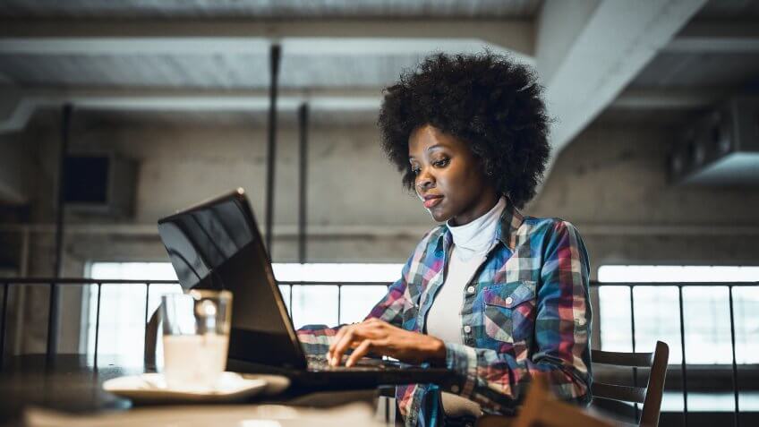 Casual woman, African-American Ethnicity, working at laptop in cafe.