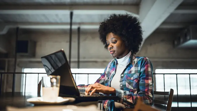 Casual woman, African-American Ethnicity, working at laptop in cafe.