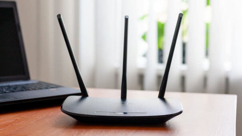 wireless wifi router and laptop at wooden table indoors.