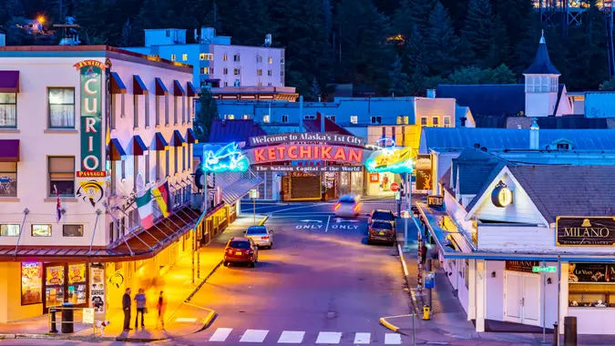 Ketchikan, Alaska - September 30 2017: Night aerial/drone view on Front Street, downtown with Welcome to Alaska 1st City neon sign, buildings, vehicles driving and parked, people walking and standing.