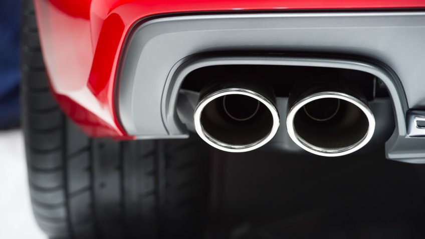 Chrome exhaust pipe of red powerful sport car bumper.