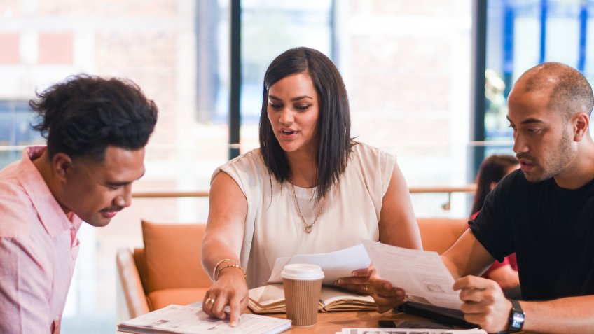 2 young New Zealand Maori males in business meeting with 1 Maori female in a modern office.