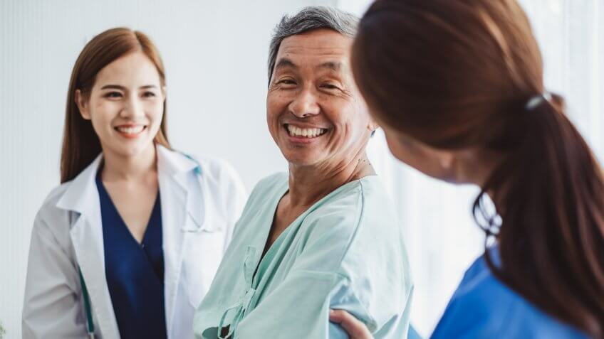 Asian doctor woman and nurse encourage disabled old man patient sitting on wheelchair at hospital, asian medical concept.