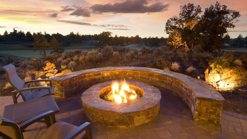 stone fire pit with outdoor chairs, enjoying the sunset and landscape.