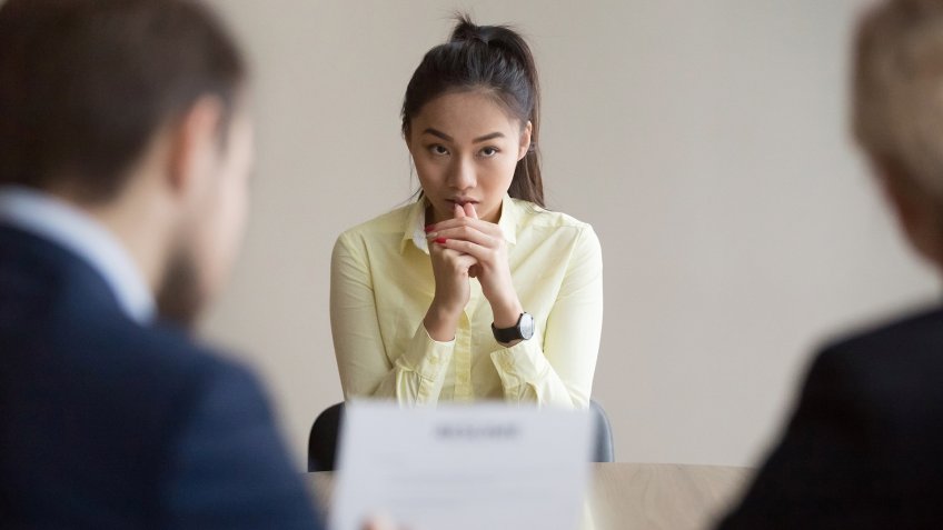 Nervous young Asian job applicant wait for recruiters question during interview in office, worried intern or trainee feel stressed applying for open position, meeting with hr managers.
