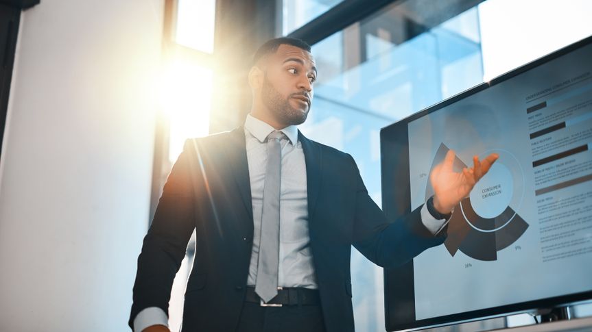 Shot of a young businessman presenting data on a screen during a meeting in an office.