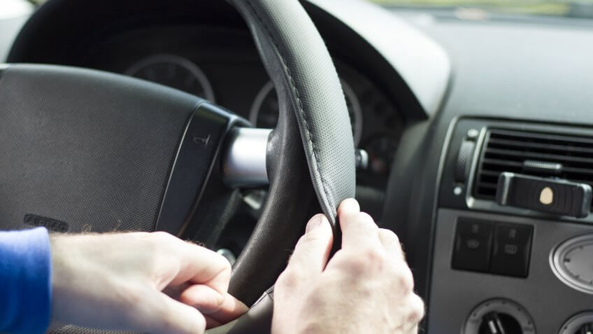 The mechanic puts on the overlay on the steering wheel of the car.