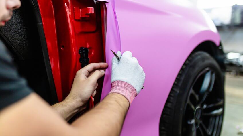 Car wrapping specialist putting vinyl foil or film on car.