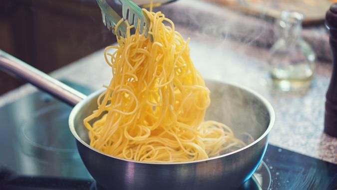 Young women preparing spaghetti alle Vongole at home.