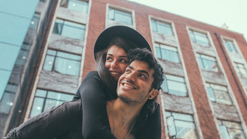 One young happy couple piggyback and smiling.
