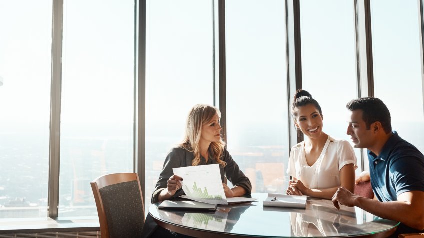 Shot of a young couple meeting with a financial planner in a modern office.