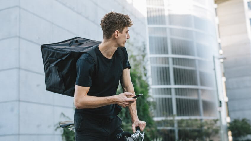 Male bicycle messenger checking directions on smartphone.