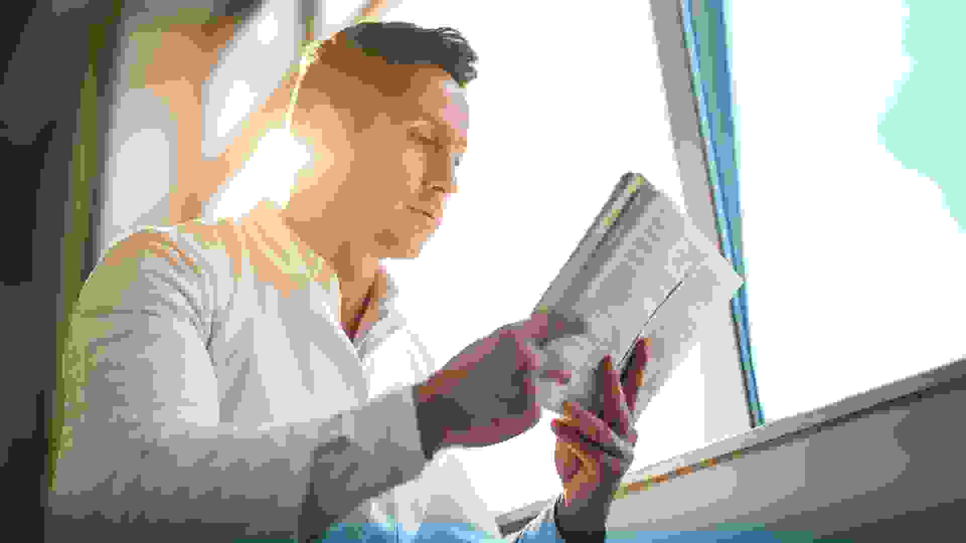 Low angle view of a mid adult doctor reading a book by the window.