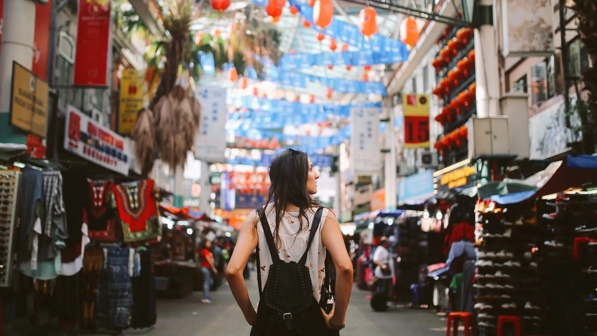 在马来西亚吉隆坡的唐人街，年轻的旅行者走过摊位。
