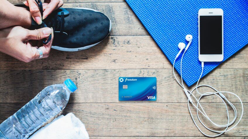 Flat lay of mobile phone with earphone and sport equipment on wood background.