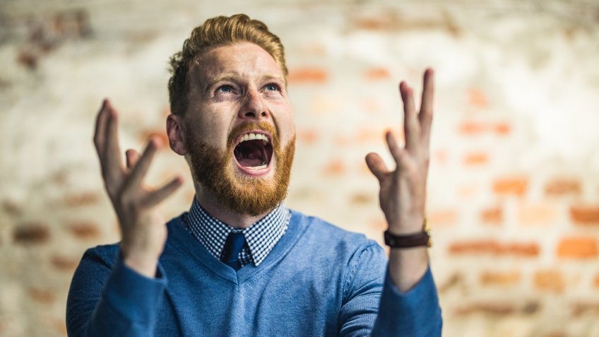 Frustrated businessman screaming of disappointment and looking up.