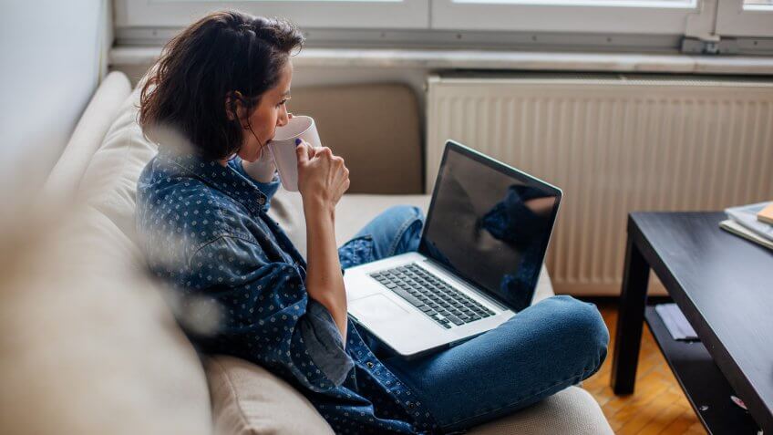 Cropped image of woman using laptop with blank screen.